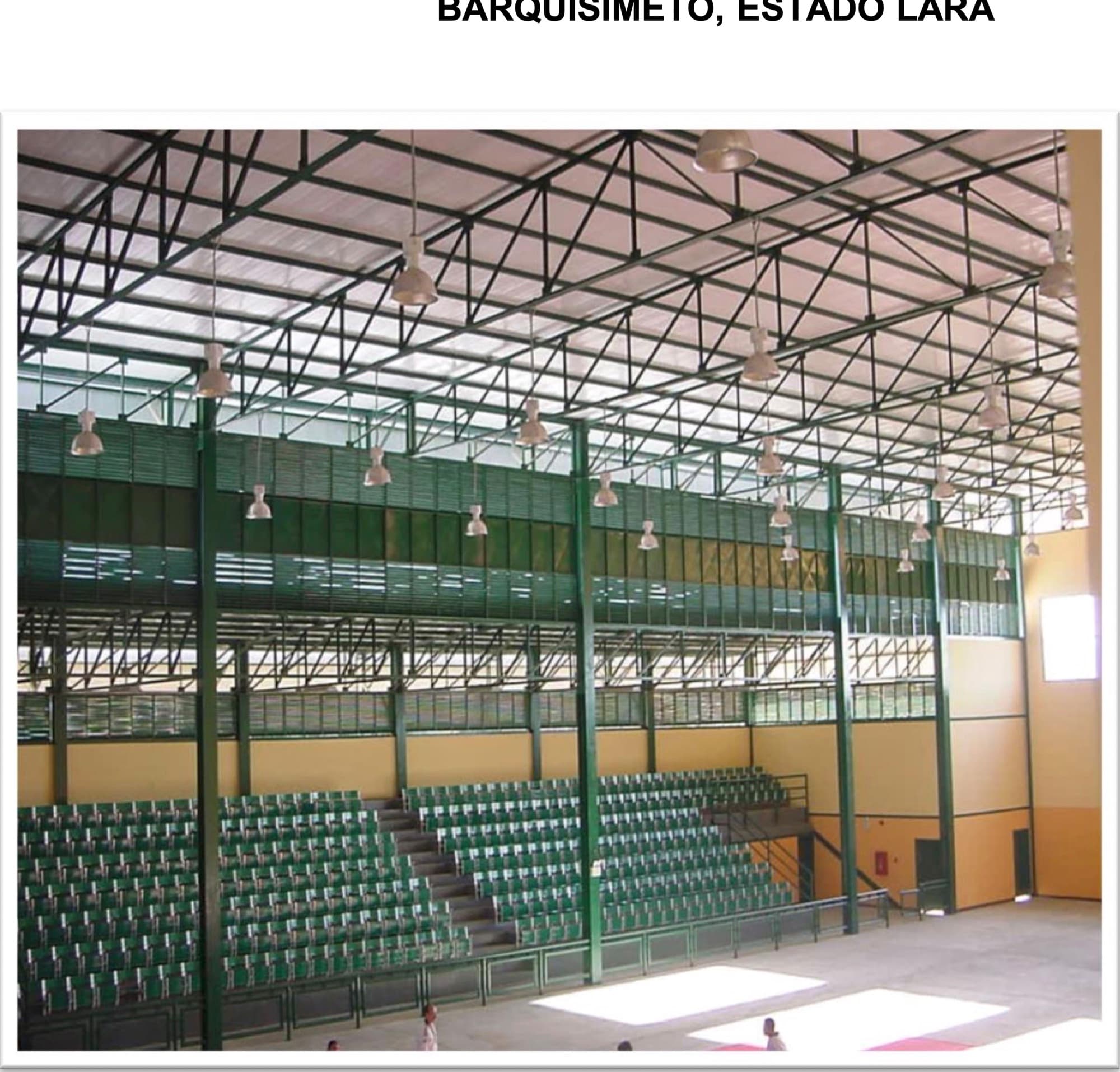 Interior de gimnasio terminado, con estructura metálica de cubierta de gran luz y graderías