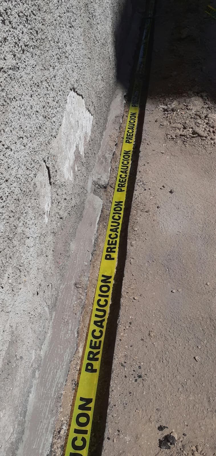 Tramo de zanja señalizado con cinta de precaución durante el reemplazo de la tubería de conexión