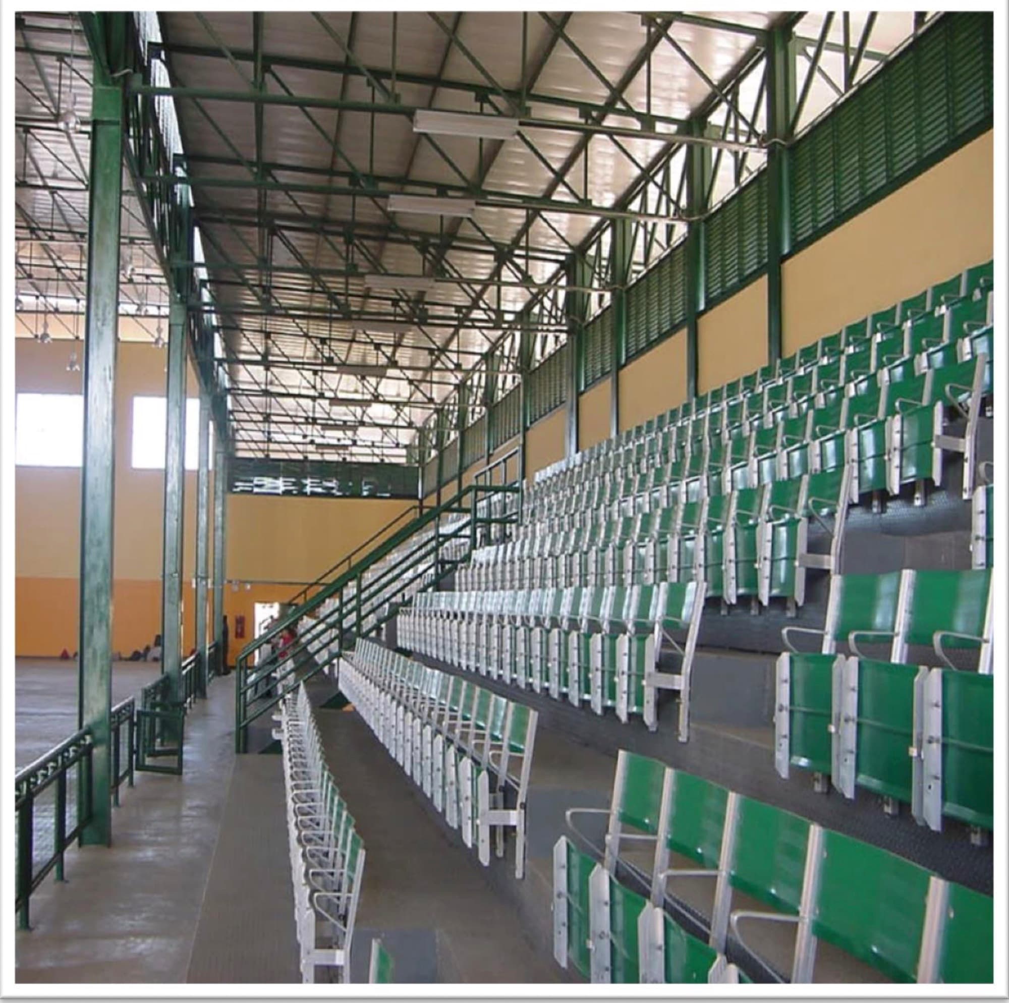 Graderías del gimnasio con butacas instaladas y estructura de cubierta a la vista